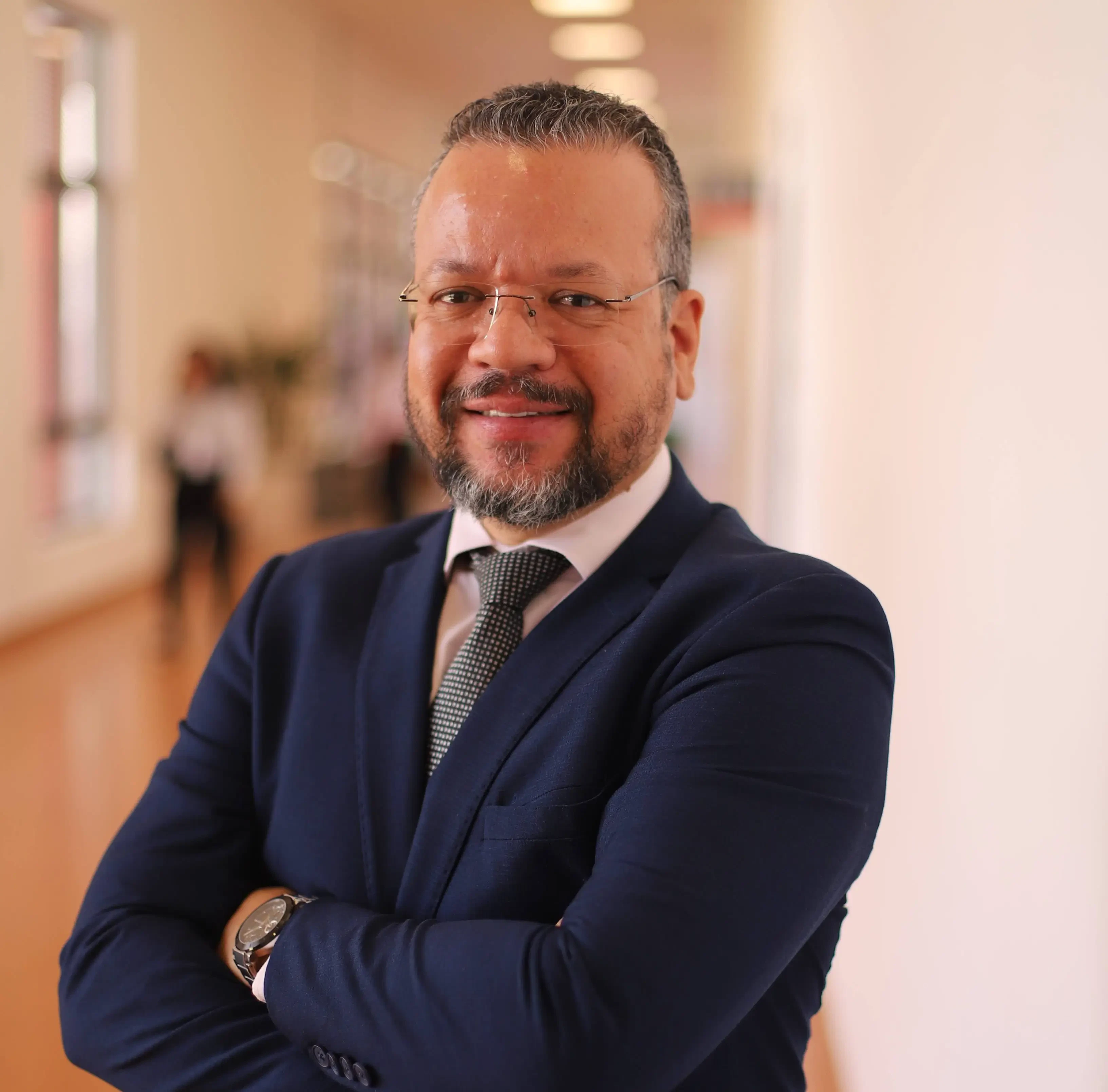 Anderson Cremasco, curador do CSC - Congresso de Supply Chain 2026, posa sorrindo de braços cruzados vestindo terno azul-marinho. Foto profissional de alta qualidade tirada no corredor do São Paulo Expo durante a feira Hospitalar.