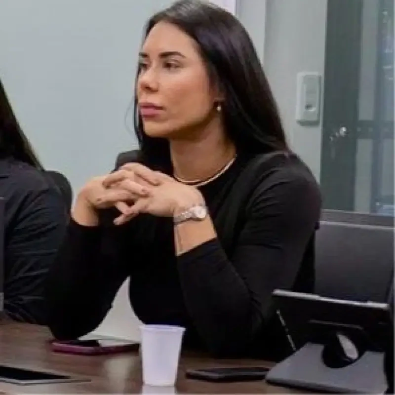 Andreia Alcantara, palestrante no Healthcare Innovation Show, sentada à mesa de reunião com mãos entrelaçadas.