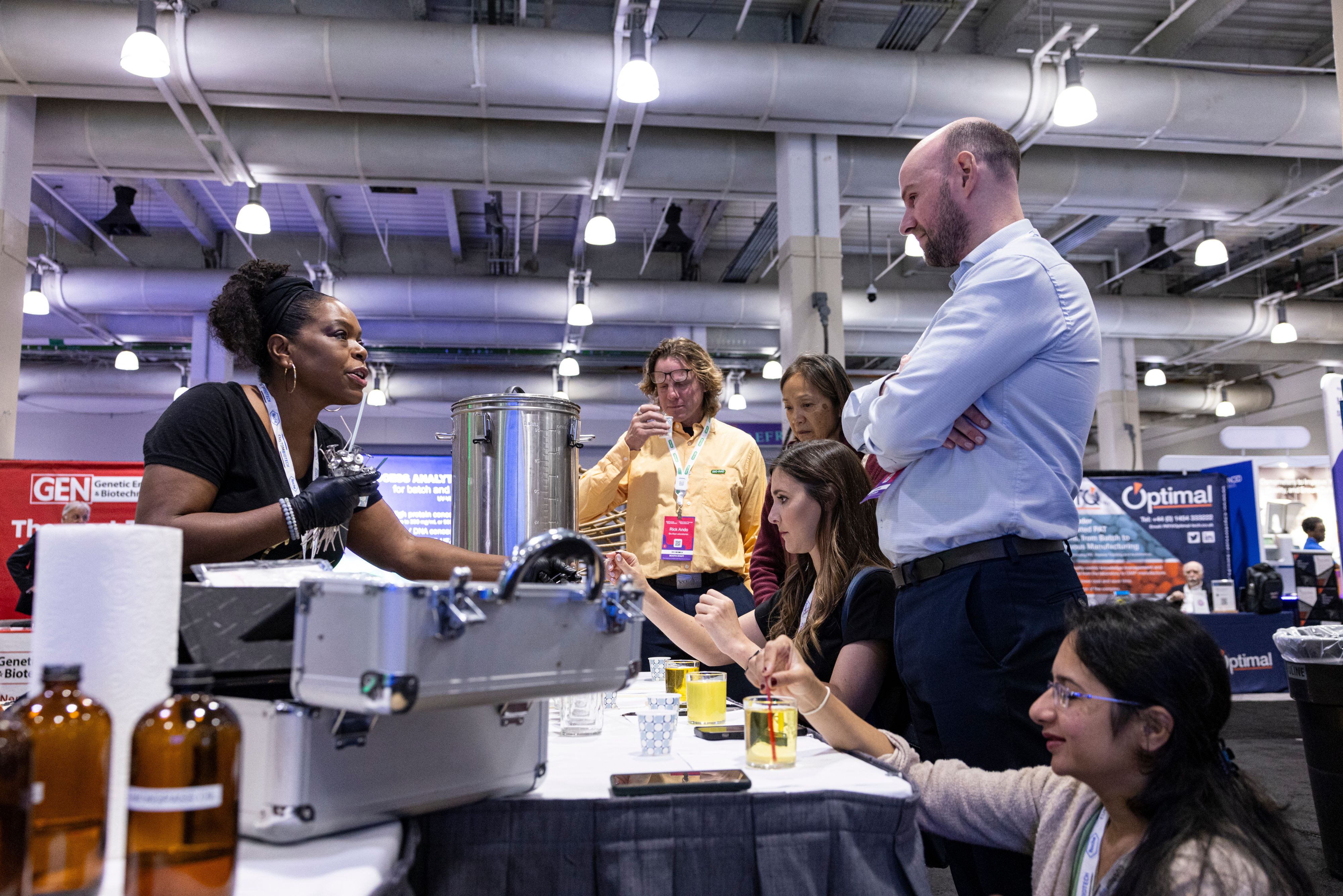 Bioprocessing attendees try perfume-making in the exhibit hall as a woman directs them.