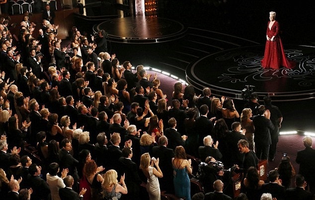 woman in red dress on stage in front of a standing ovation