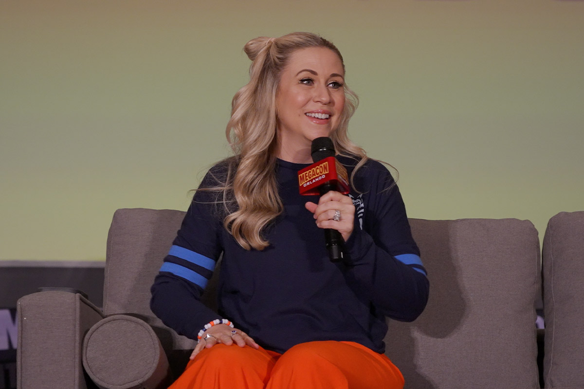 Ashley Eckstein smiles holding a microphone