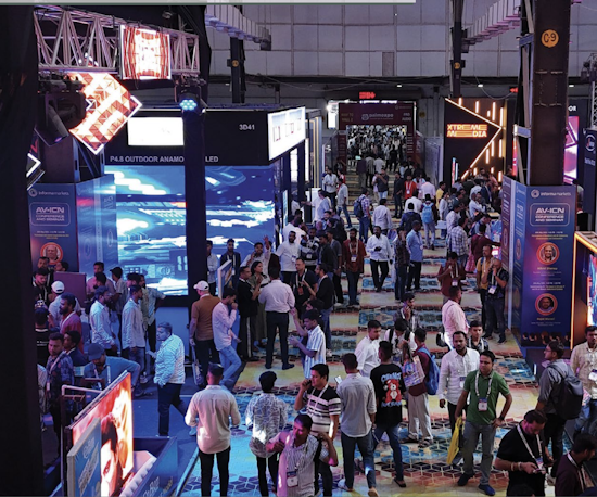 Crowded aisles at the AV-ICN trade fair with attendees walking through the exhibition area.