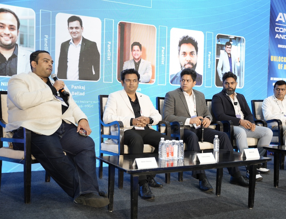 Panel discussion at AV-ICN conference with five speakers seated on stage.