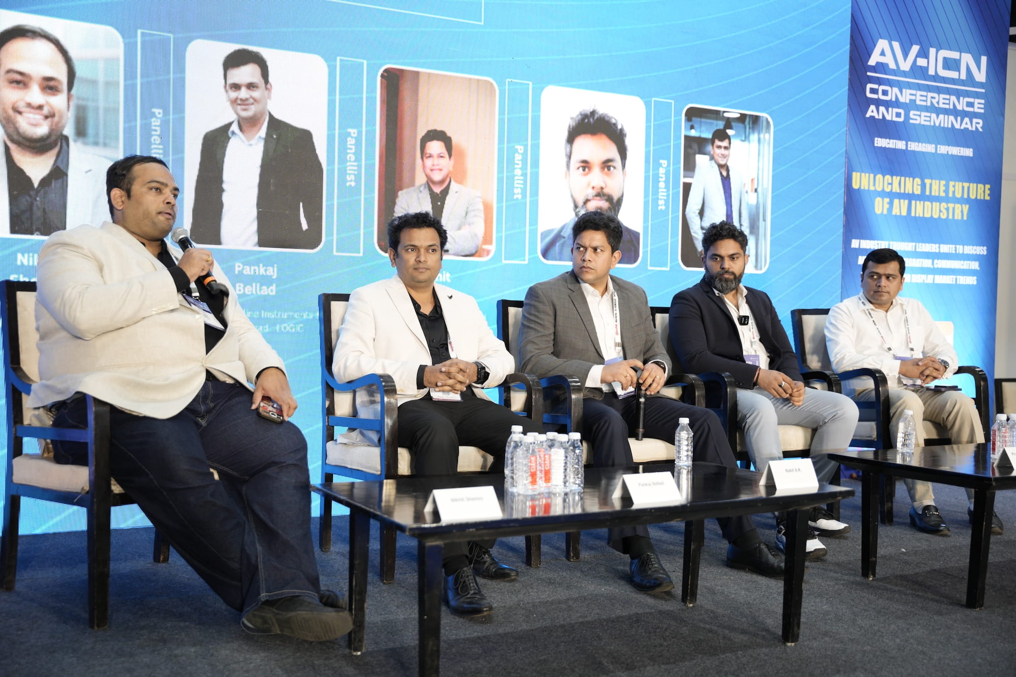 Panel discussion at AV-ICN conference with five speakers seated on stage.