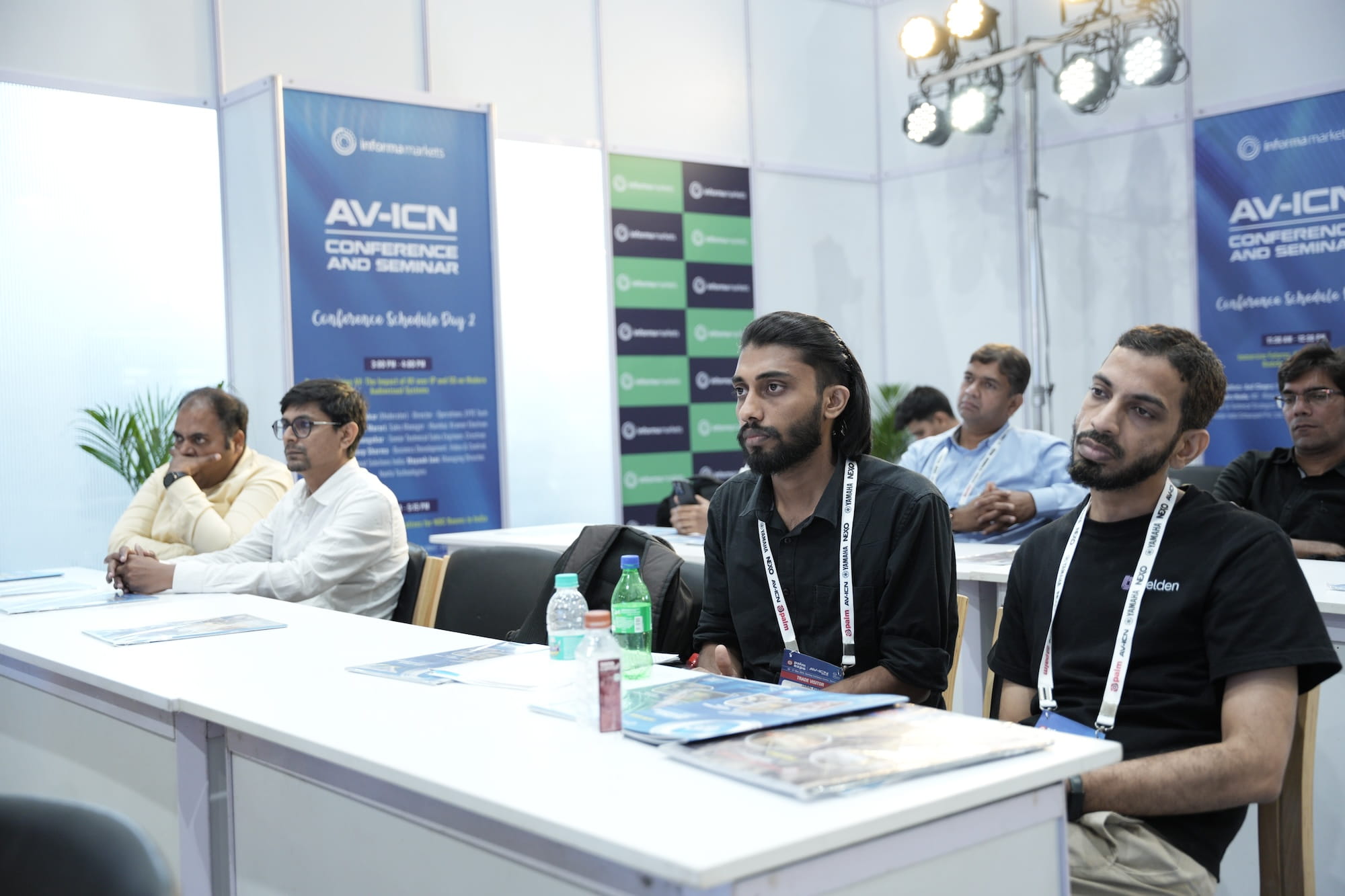 Attendees at an AV-ICN conference sitting at a panel table with name badges.