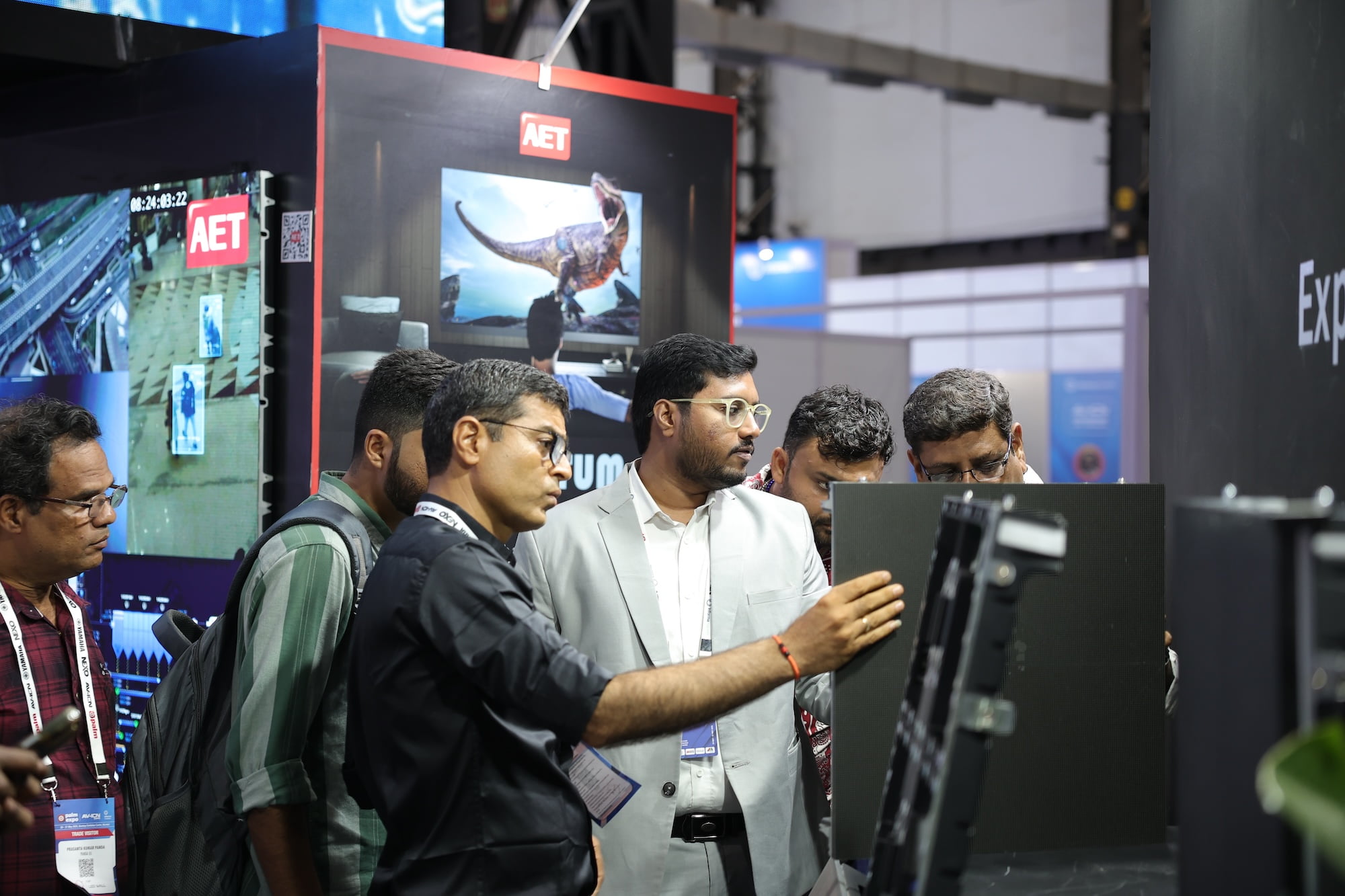Image -Crowded event technology trade show booth with large screens and an image of a yellow sports car.