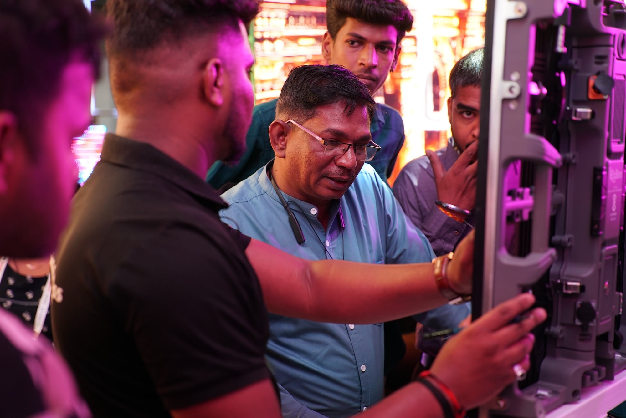 Exhibitor presenting technical equipment to a group of attendees.