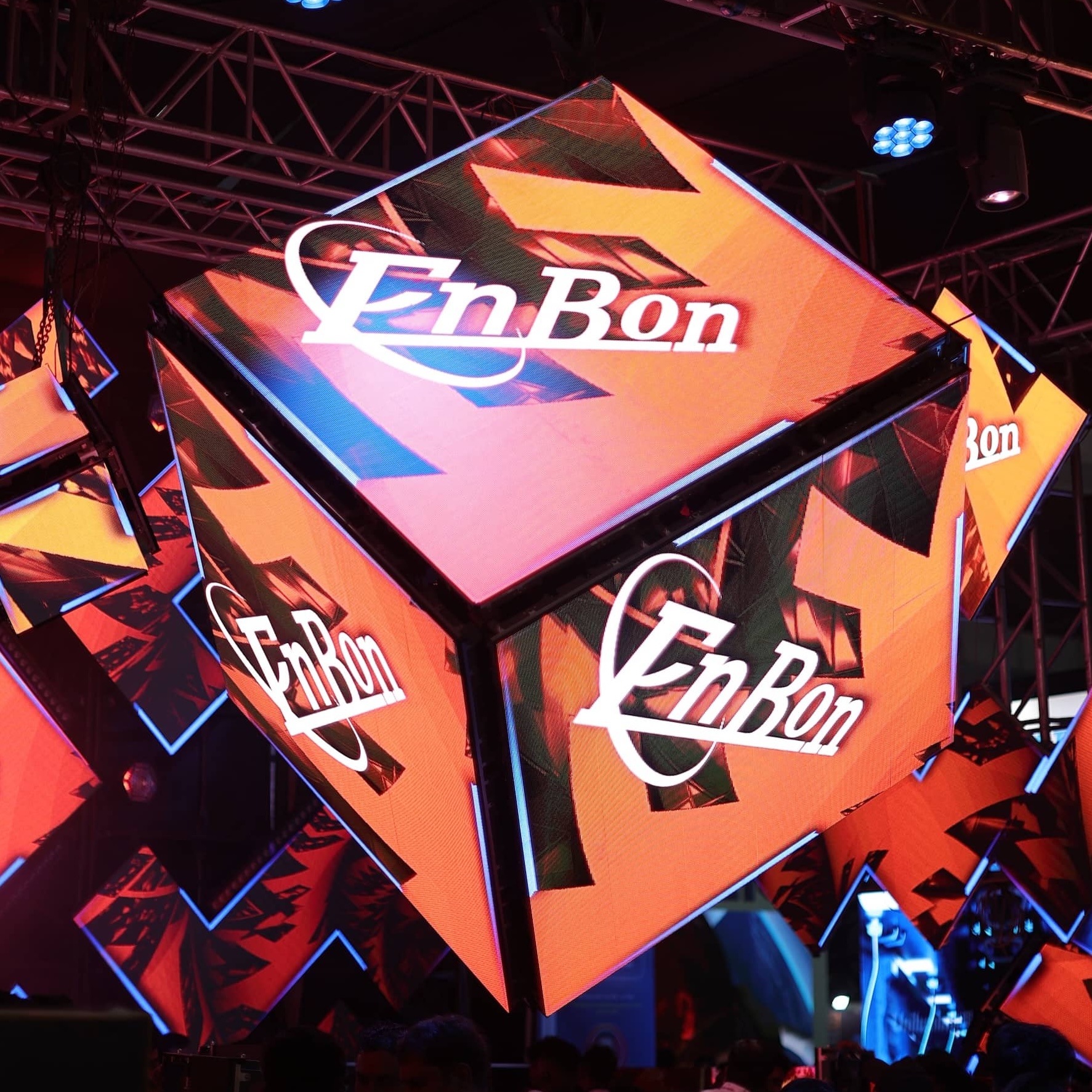 Illuminated EnBon branded cubes at an event venue with stage lighting and truss structures.