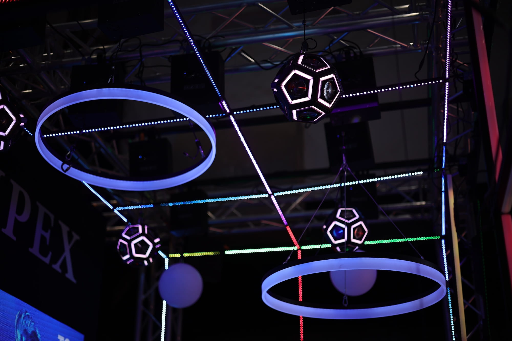 Futuristic light installation with glowing rings and geometric shapes hanging from ceiling.