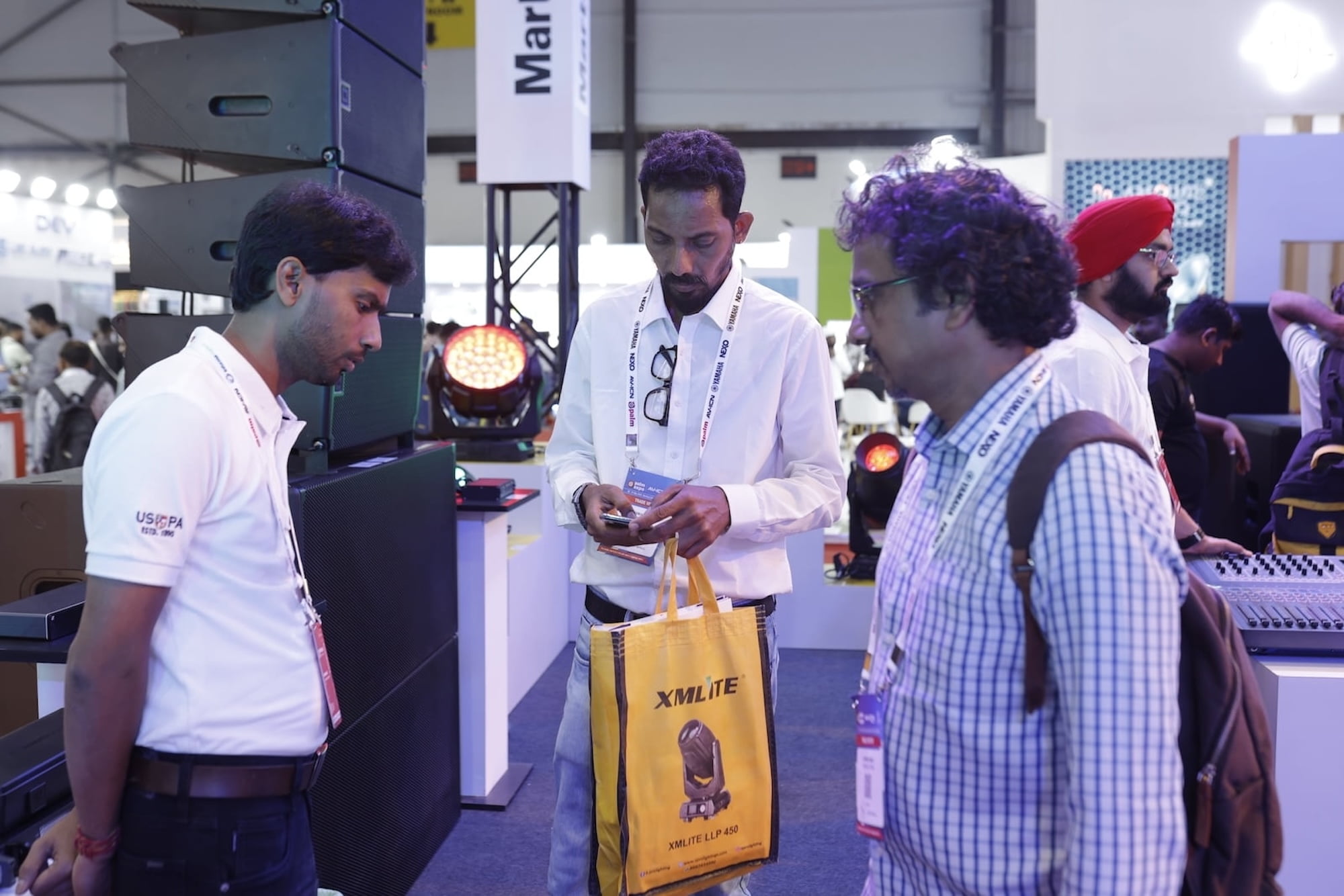 People examining lighting equipment at a trade show or exhibition.