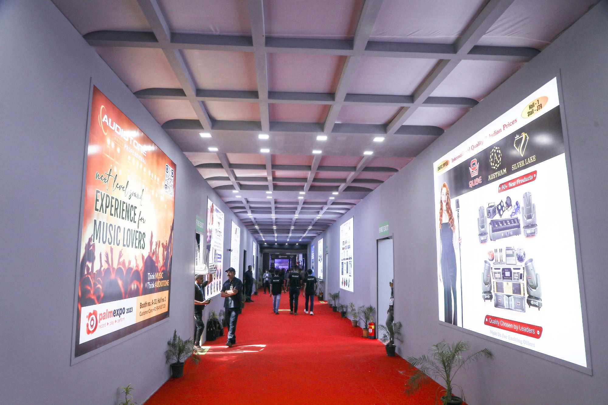 Exhibition hallway with red carpet and illuminated advertising displays on both walls.