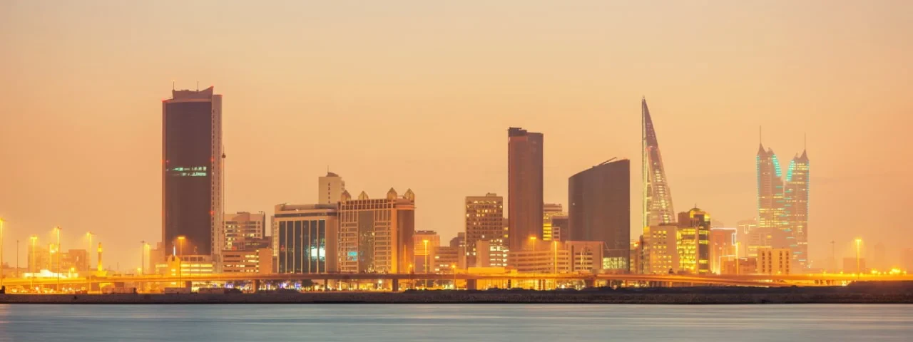 A city skyline illuminated by twilight, showcasing buildings against a colorful dusk sky.