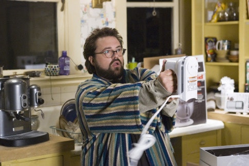 Kevin Smith as Sam is in a kitchen. He is wearing a stripped robe. He is holding a handheld electric mixer (with no whisks), defensively.