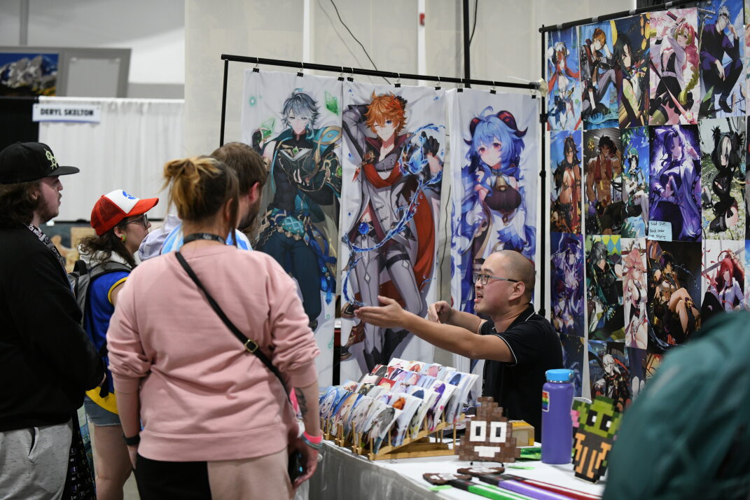 Anime for all - a group gathers to talk product with a vendor selling anime pillows, art, postcards, and more.