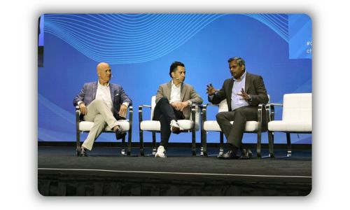 A photo of three men sitting onstage participating in a panel discussion.