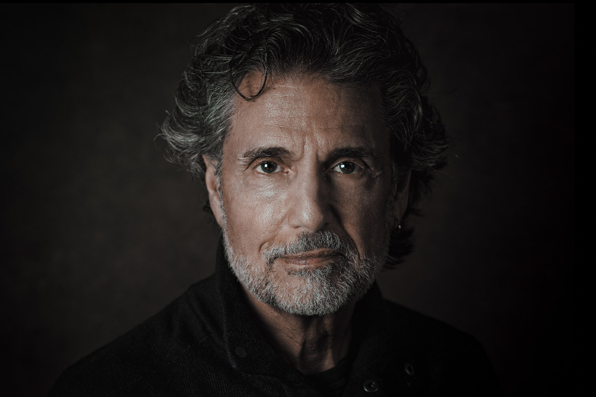 Chris Sarandon poses with a slight smirk in a black shirt