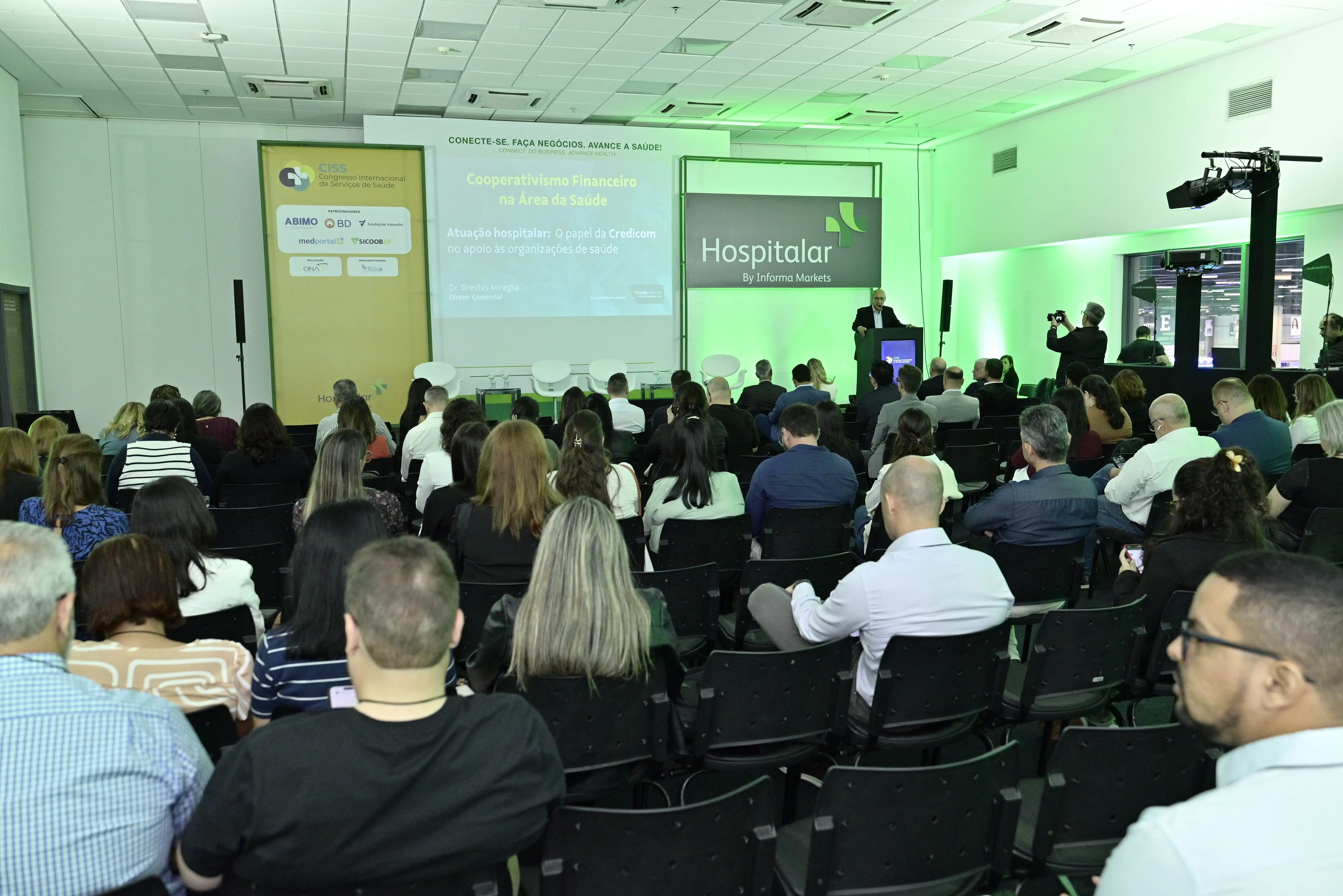 Palestrante conduz votação interativa sobre cooperativismo financeiro na área da saúde durante a feira Hospitalar.