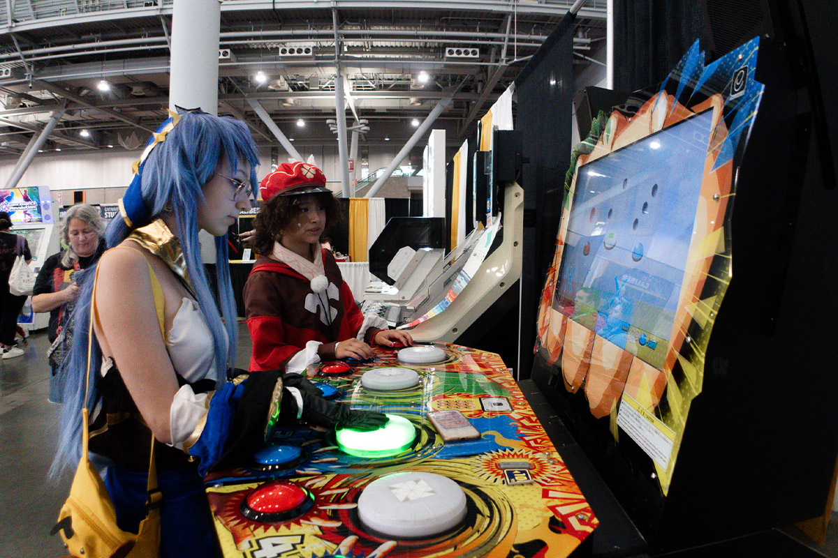 fans in cosplay play an arcade game