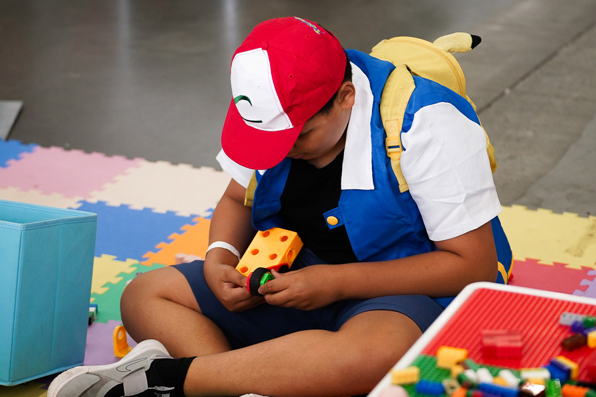 a fan dressed as Ash Ketchum plays with a toy