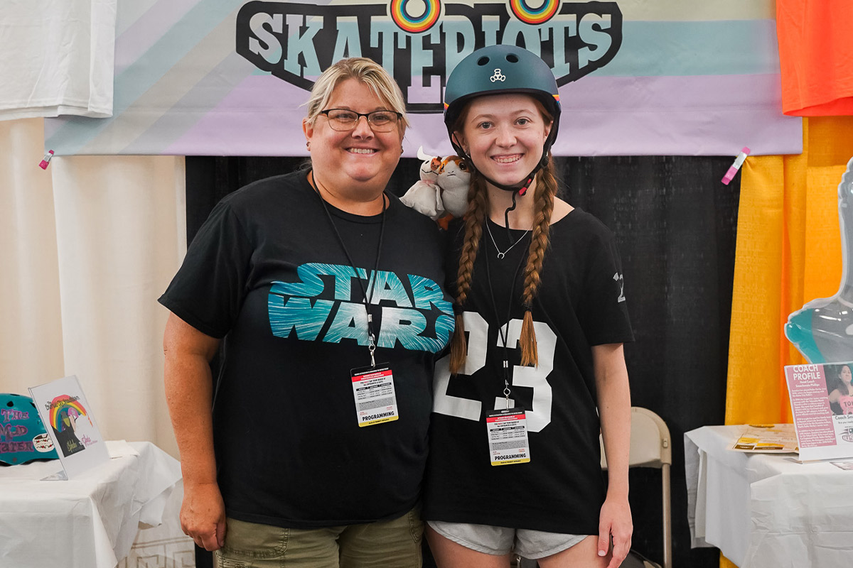 two fans pose smiling for a photo next to eachother