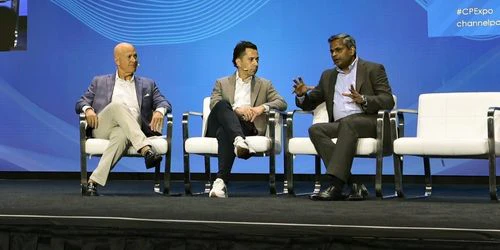 A photo of three men sitting onstage participating in a panel discussion.