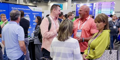 A photo of four people talking to one another on a busy trade show floor.