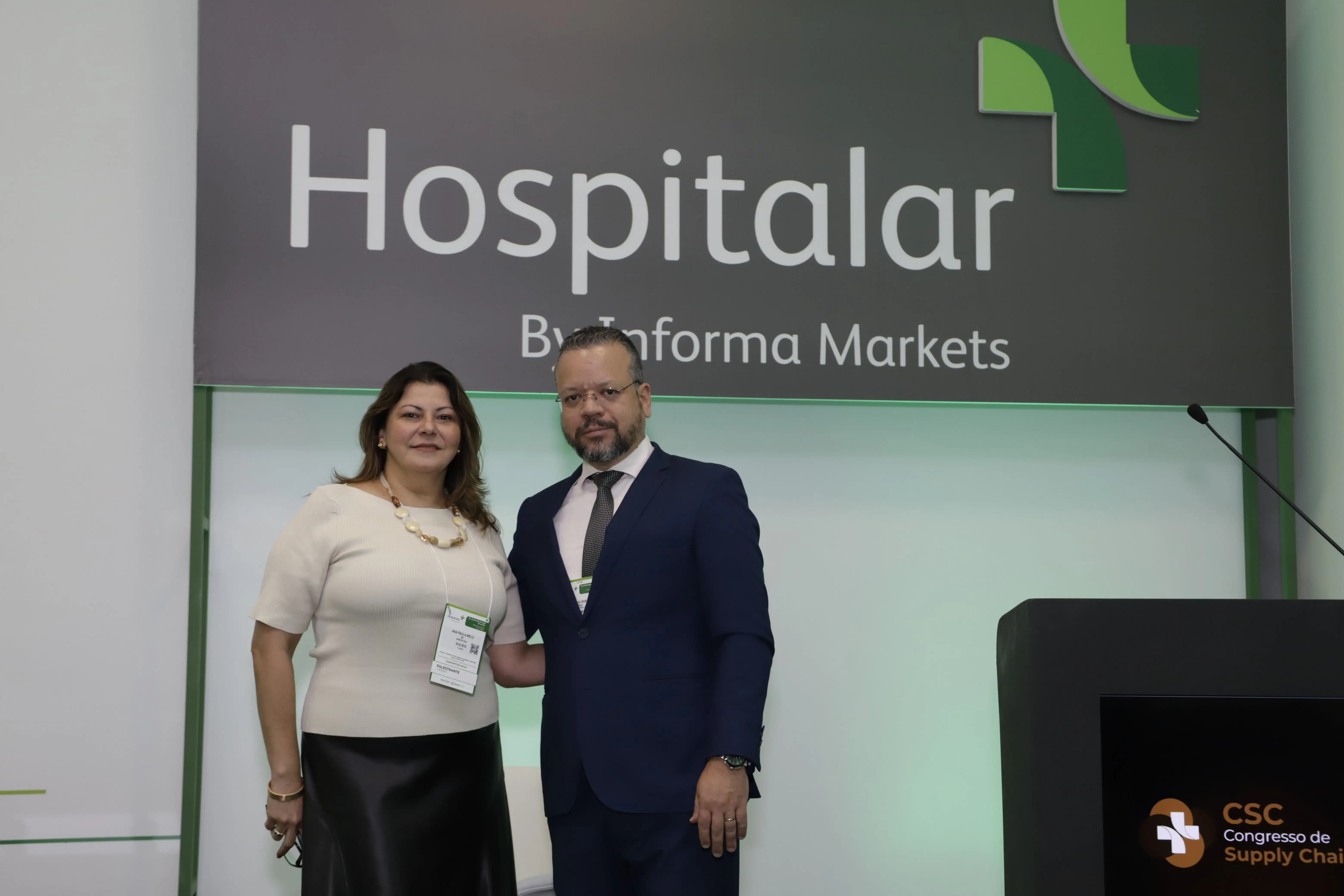 Palestrante no CSC Congresso de Supply Chain 2026 sorri e aponta para a plateia durante conferência sobre supply chain. No palco, púlpito com microfone e painel de fundo com logotipos de patrocinadores como Gedanken, GTP Plan e Labor.