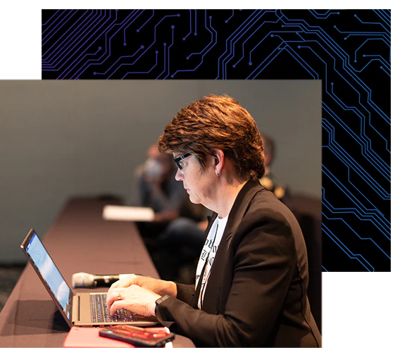 Attendee taking notes on her laptop during a conference session