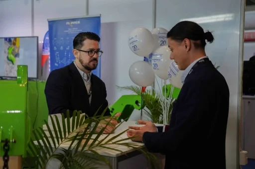 Exhibitors speaking with a visitor at an event booth.