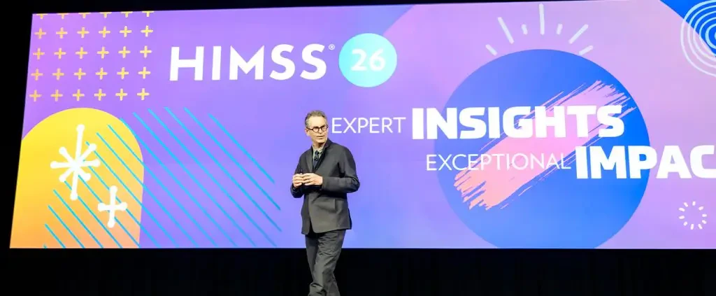 Palestrante no palco do evento HIMSS 26 abordando temas de saúde business e inovação tecnológica. Imagem relacionada ao conteúdo do e-book sobre impacto e insights excepcionais no setor de saúde.