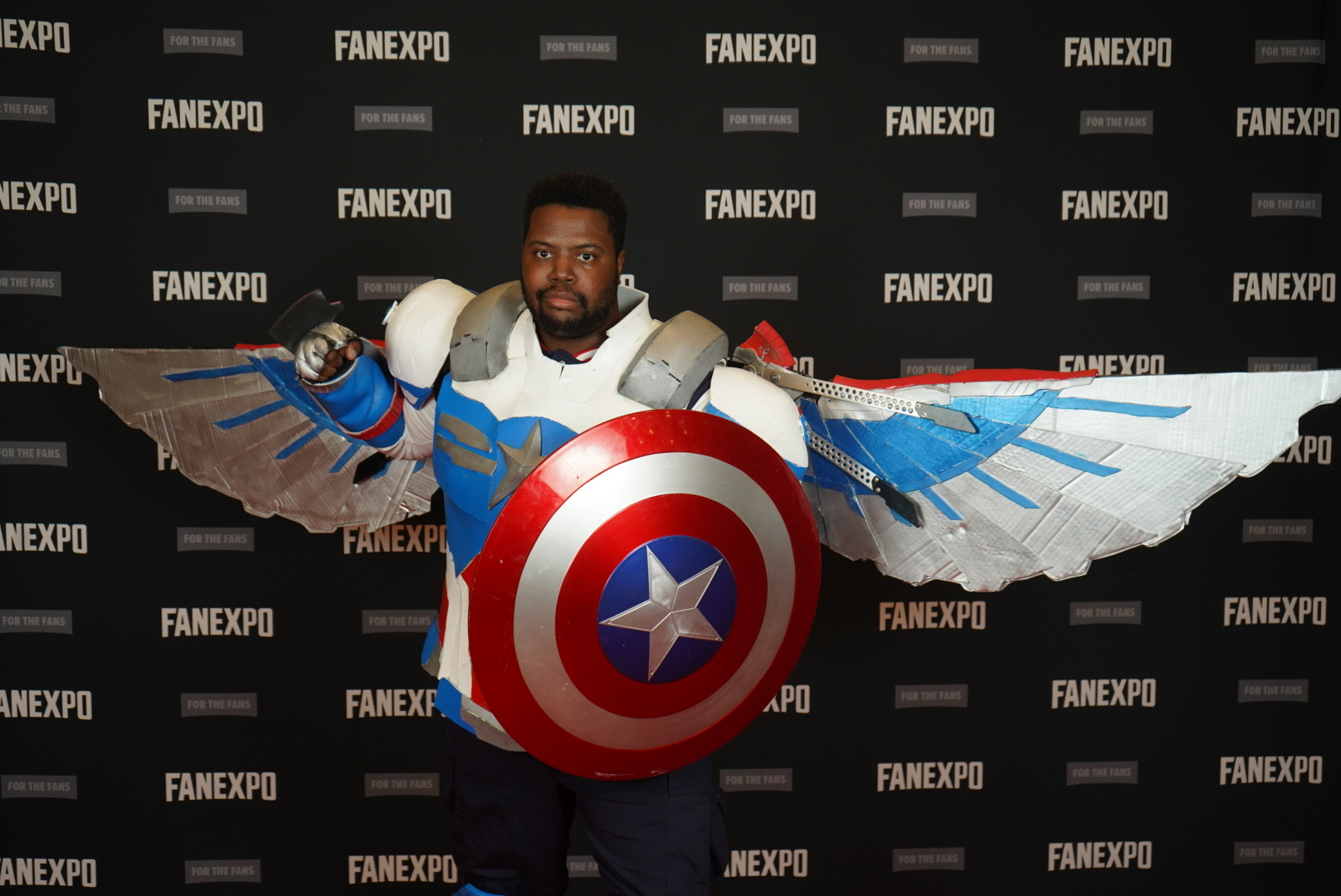 Cosplayer as homemade Captain America from Falcon and the Winter Soldier. In the background, is the FAN EXPO background that repeats FAN EXPO..