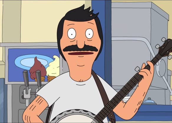 Bob stands behind the counter of the restaurant, in front of the order window and ice cream machine. He smiles as he plays the banjo