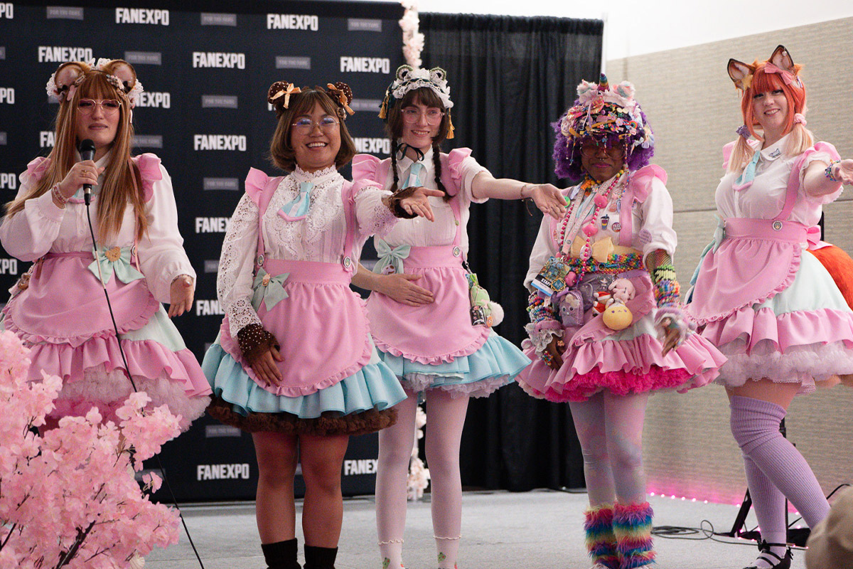 cosplayers in maid atire dance and point at fans