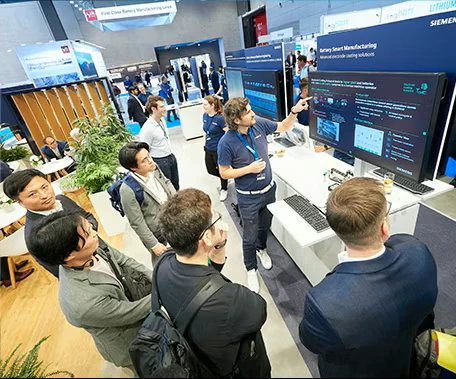 Several individuals are engaged with a digital display, examining the information presented at an exhibition.