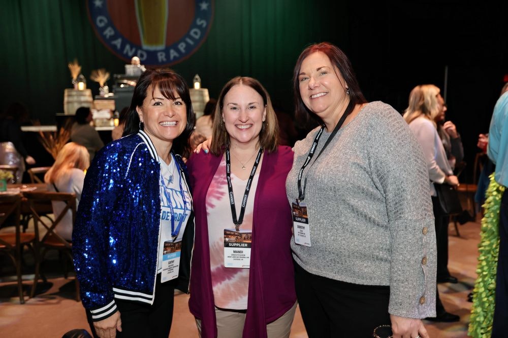Three women smiling and enjoying an opening reception.