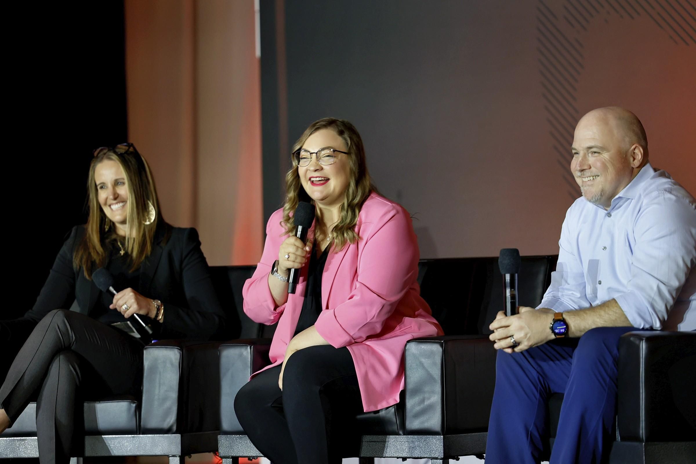 Two women and one man on stage on eTourism Summit laughing and smiling during their session.