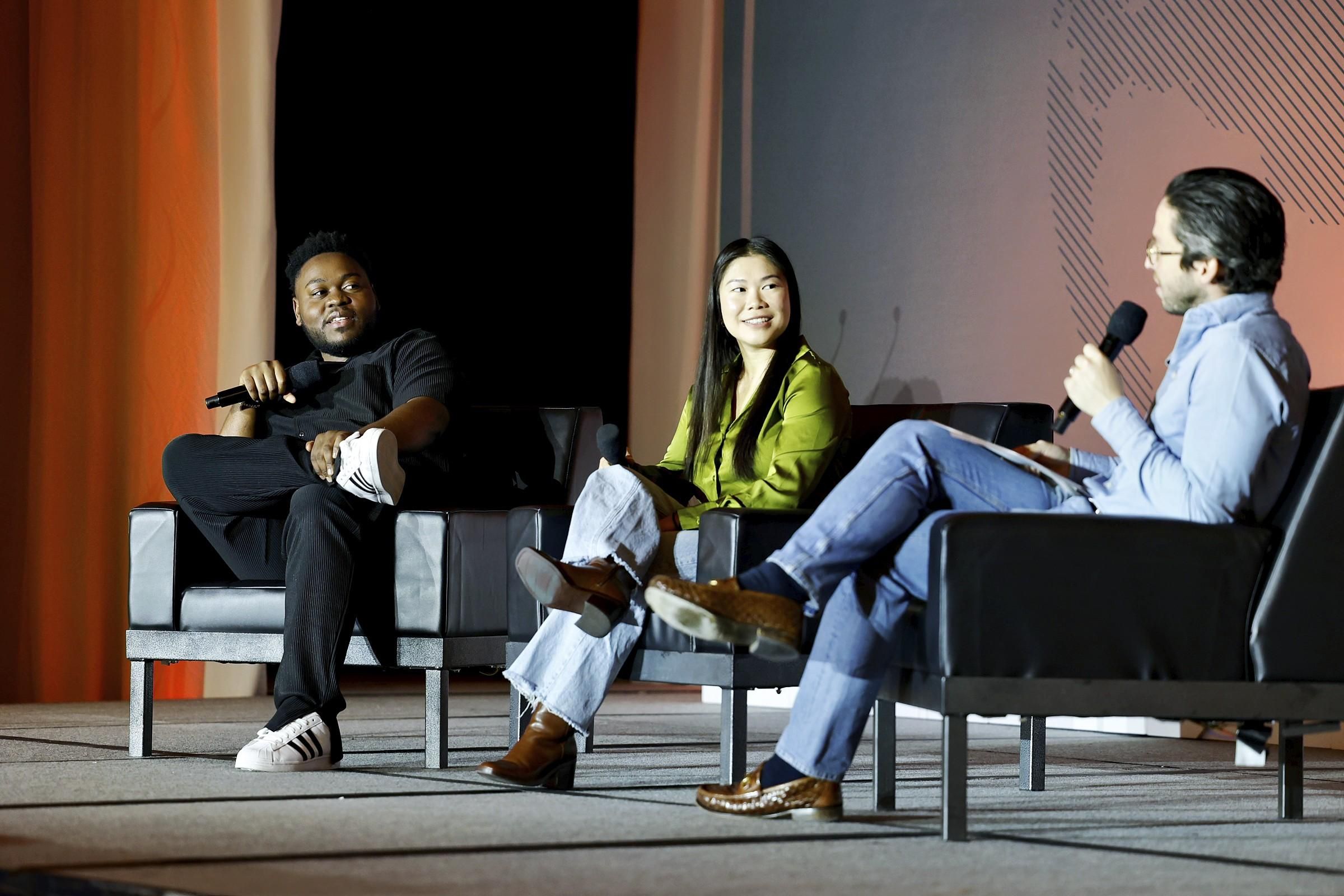 Two men and one woman sitting on stage at eToursim Summit having a panel discussion.