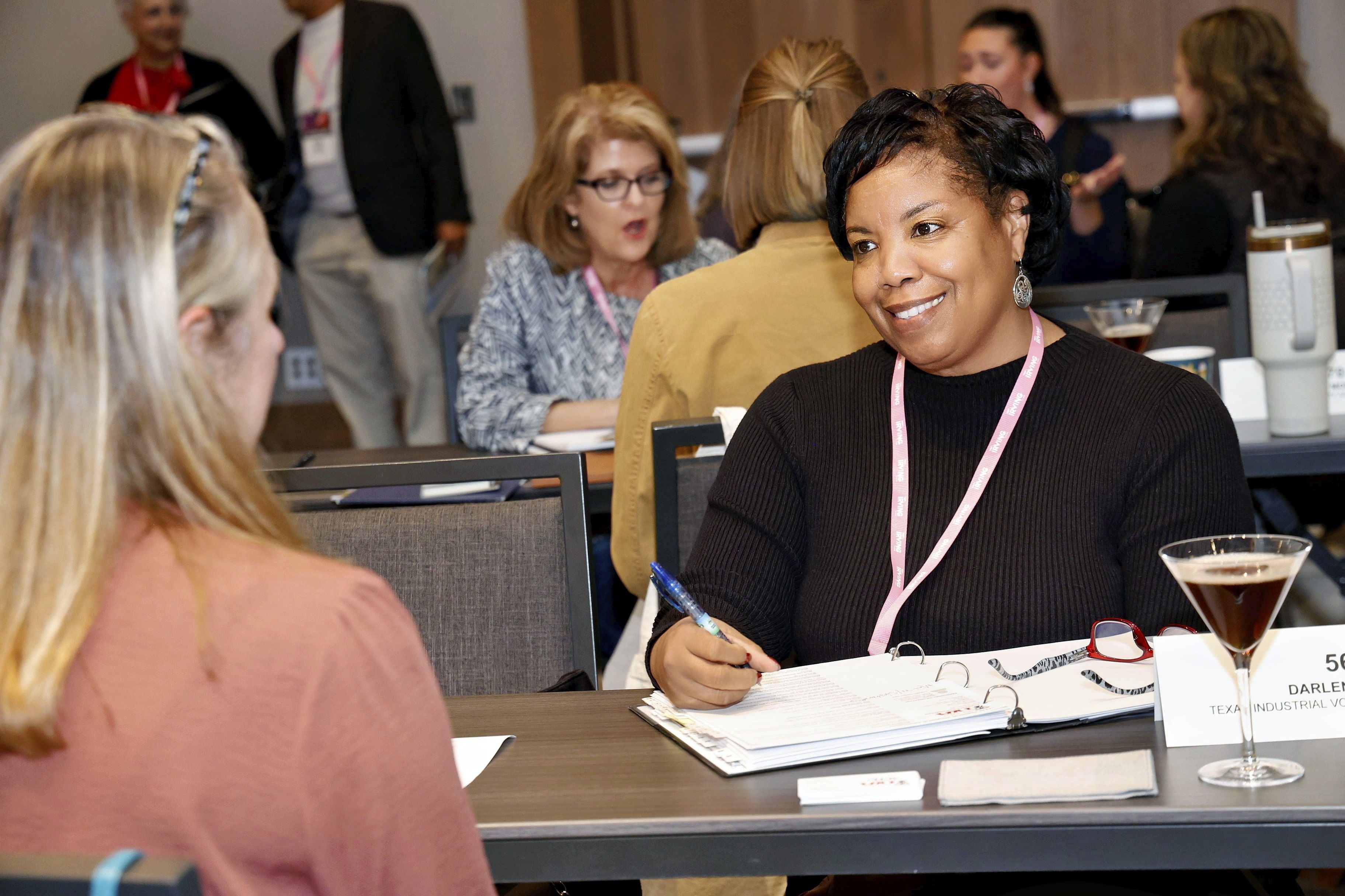 A woman smiling and taking notes during one-on-one appointments at Connect Texas.