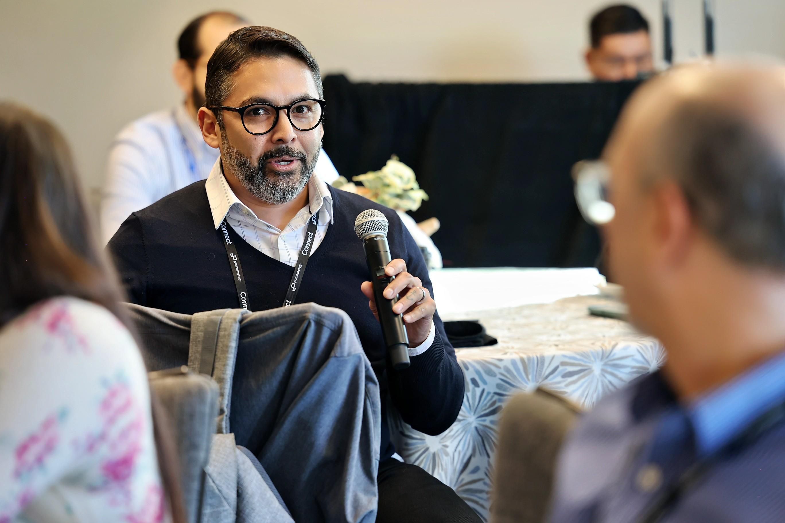 A man speaking into a microphone during a roundtable session.