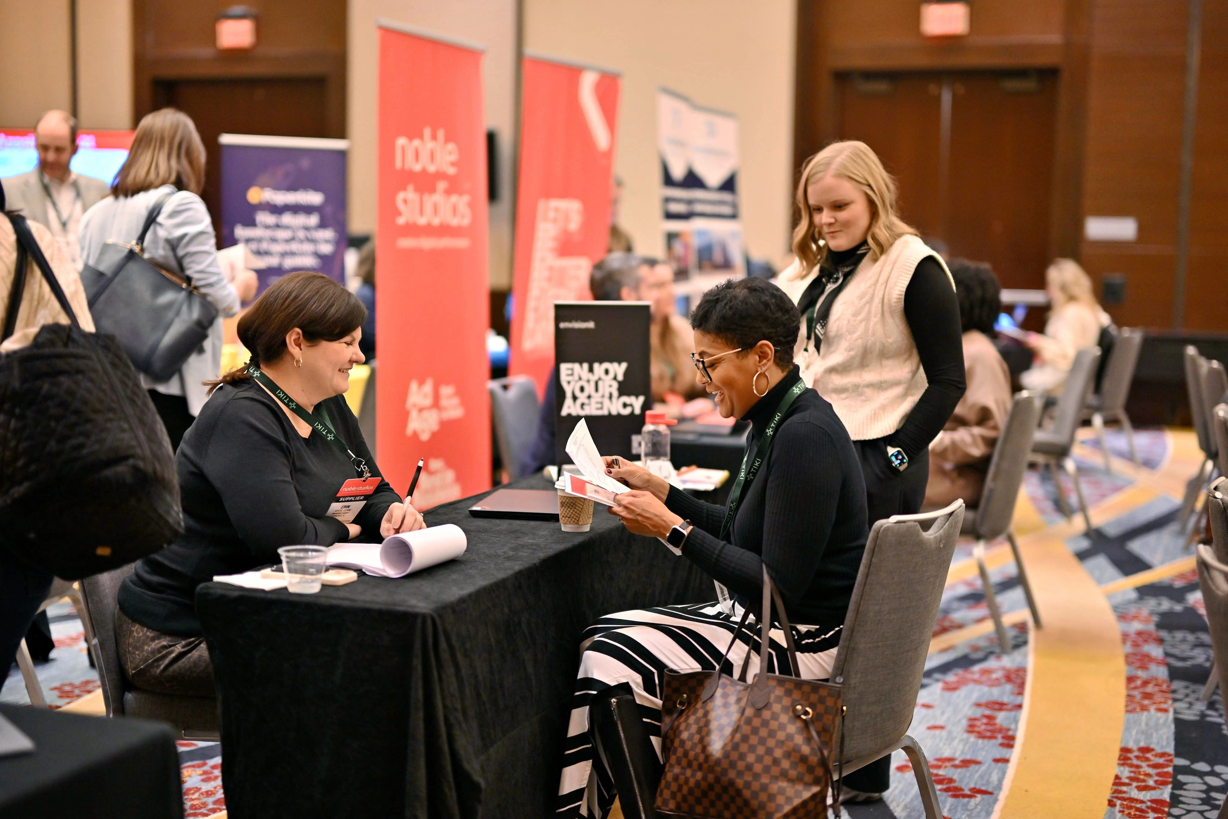Group of three women smiling and holding drinks at a networking party