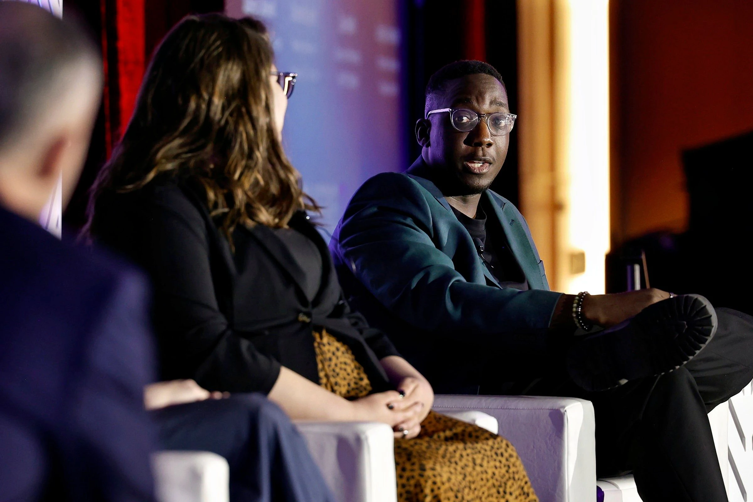 Two women and one man on stage smiling and holding their awards.