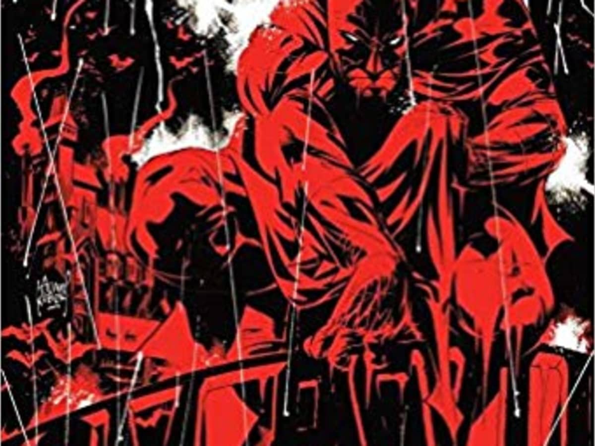 Batman in red and black perched on a railing as it rains.