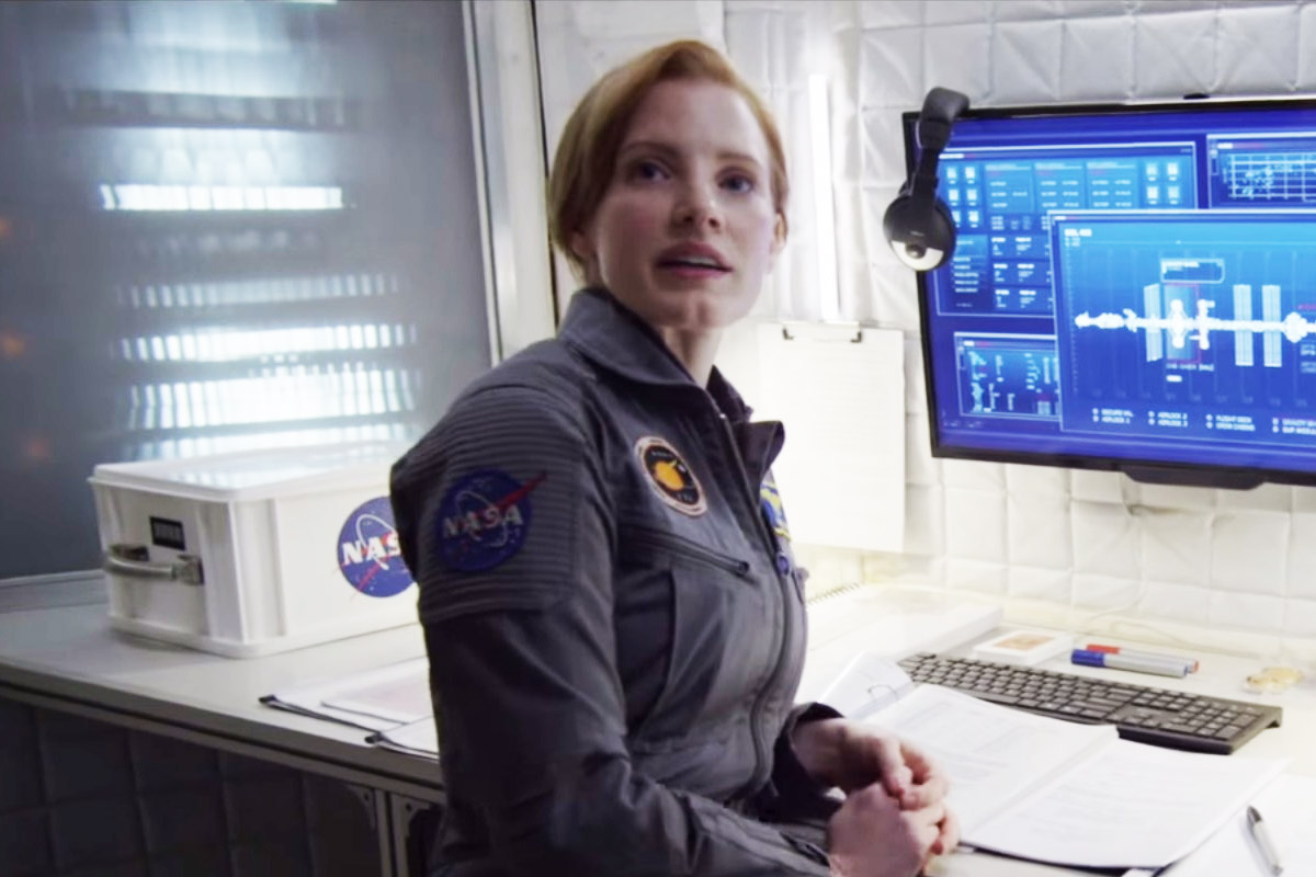 Commander Lewis looks at the camera next to a NASA computer