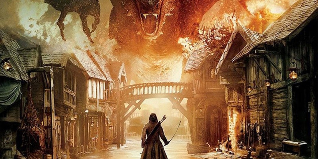 A dragon rips through the town, shrouded in flames. Bard the Bowman stands with his back to the screen, ready to fire.