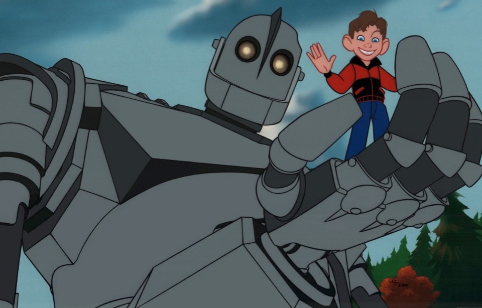 The Iron Giant holds a small child in his hands as the child laughs