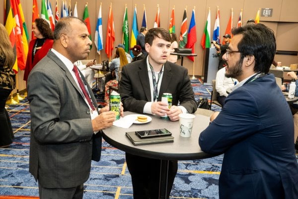 3 attendees eating and drinking at the international reception