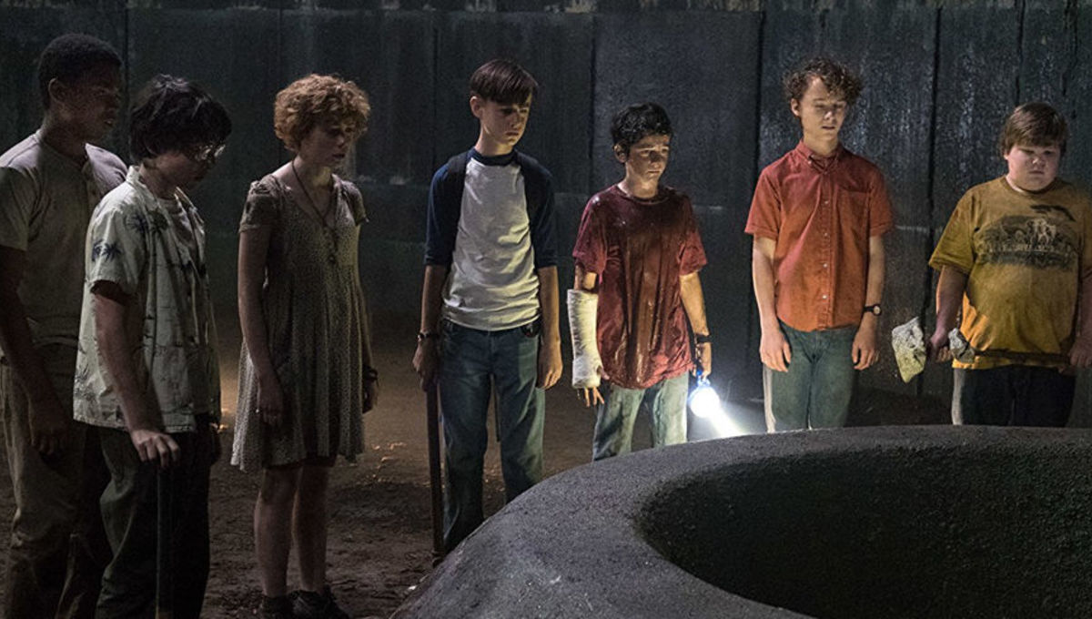 The children from the IT movie stand side by side with a flash light looking down a large well