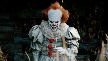 Pennywise stands there holding the string of a balloon. He stares directly into the camera.
