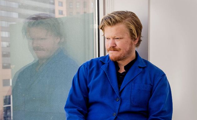 Jesse Plemons in a blue shirt looking at his reflection