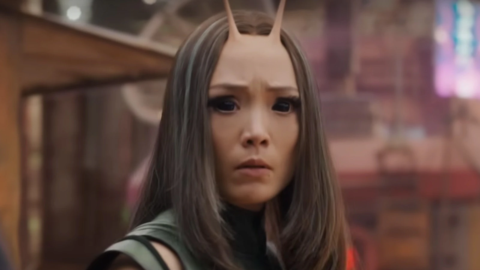 Mantis, the character from Guardians of the Galaxy is wearing a green outfit and is looking straight into the camera. She looks worried.